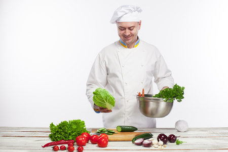 The chef cooking fresh vegetable salad in his kitchen on white backgroundの写真素材