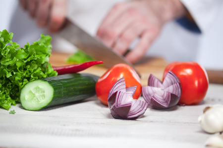 The hands of chef cutting a green lettuce in his kitchen on white backgroundの写真素材