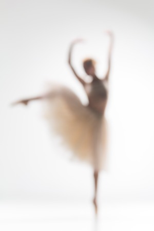 Blurred silhouette of ballerina dancing on white background