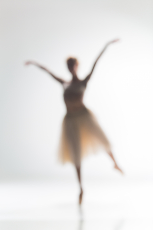 Blurred silhouette of ballerina dancing on white backgroundの写真素材