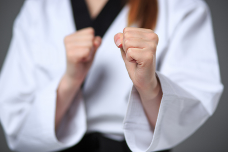 The hands of karate girl in white kimono and black belt training karate over gray background.の写真素材
