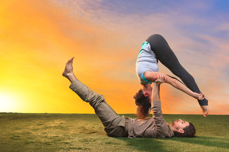 The two people doing yoga exercises against sunset skyの写真素材