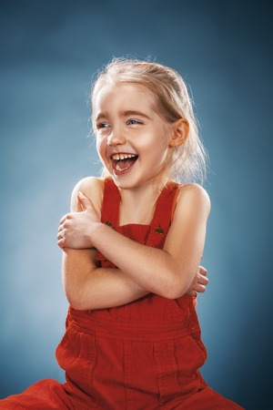 The beautiful portrait of a happy little smiling girl in red dress on blueの写真素材