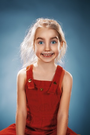 The beautiful portrait of a happy little smiling girl in red dress on blueの写真素材