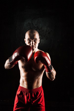 The young male athlete kickboxing on a black backgroundの写真素材