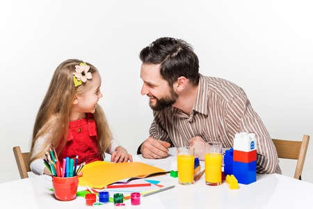 The daughter and father drawing and writing together on white backgroundの写真素材