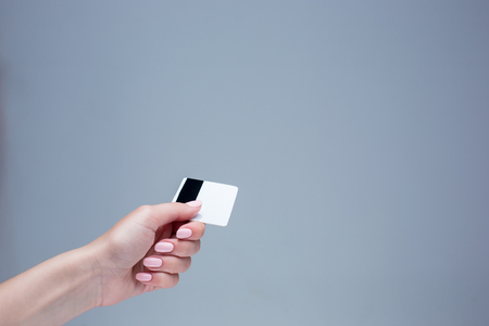 The card in a female hand is on a gray backgroundの写真素材
