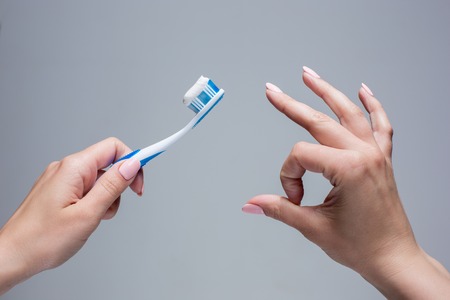 Toothbrush in woman's hands on gray backgroundの写真素材