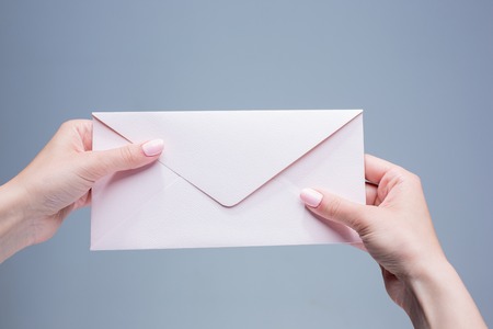 The female hands with the envelope against the gray backgroundの写真素材