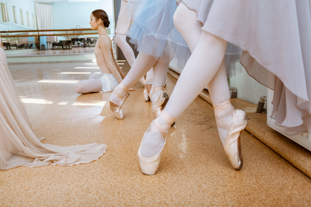 The close-up feet of young ballerinas in pointe shoes against the floorの写真素材