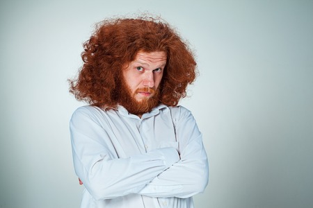 Portrait of young man with long red hair and with shocked facial expression on gray backgroundの写真素材