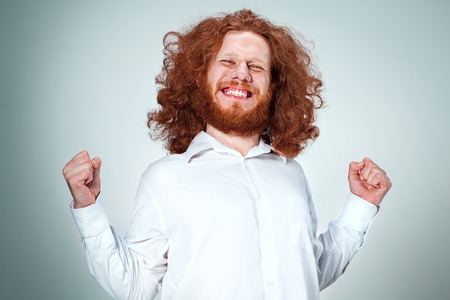 The young smiling man with long red hair looking at camera