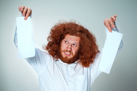 The angry man tearing out paper on grayの写真素材