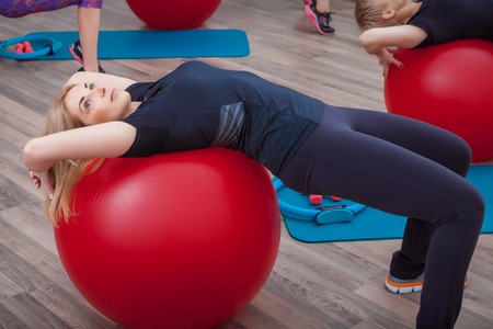 Beautiful slim doing some gymnastics at the gym with fitballの写真素材