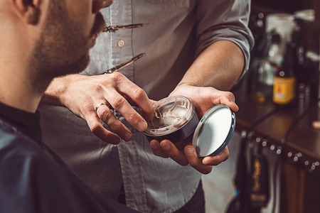 Hipster client visiting barber shop. The hands of young barber making the cut of beardの写真素材