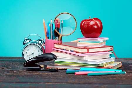 Back to School concept. Books, colored pencils and clock on blue background