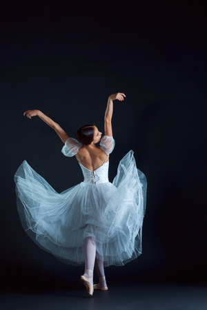 Portrait of the classical ballerina in white dress on the black backgroundの写真素材