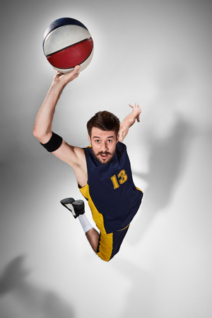 Full length portrait of a basketball player with a ball against gray studio backgroundの写真素材
