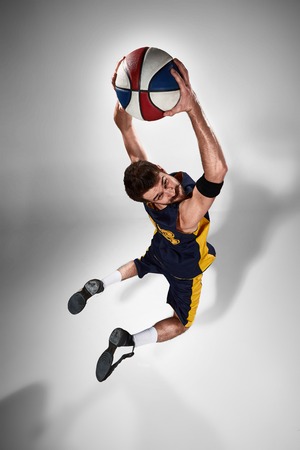 Full length portrait of a basketball player with a ball against gray studio backgroundの写真素材