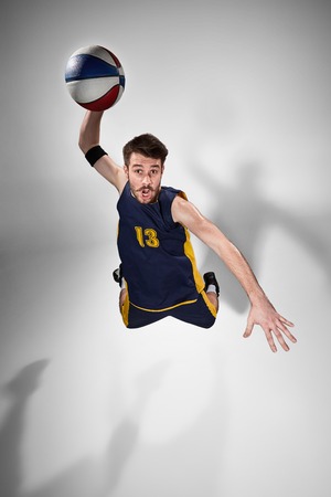 Full length portrait of a basketball player with a ball against gray studio background