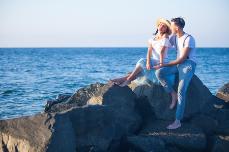 Happy young romantic couple relaxing on the beach, watching the sunsetの写真素材