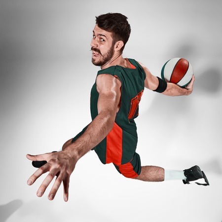 Full length portrait of a basketball player with a ball against gray studio backgroundの写真素材