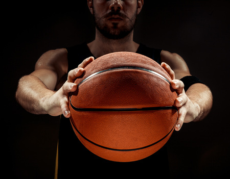The silhouette view of a basketball player holding basket ball on black background. The hands and ball close upの写真素材