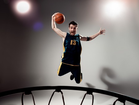 Full length portrait of a basketball player with a ball against gray studio background