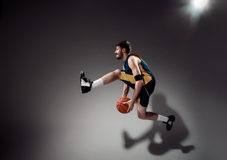 Full length portrait of a basketball player with a ball against gray studio backgroundの写真素材