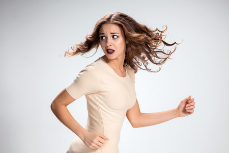 The young woman's portrait with frightened emotions on gray backgroundの写真素材