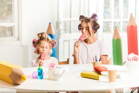 Little girl eating ice cream with her mother on whiteの写真素材