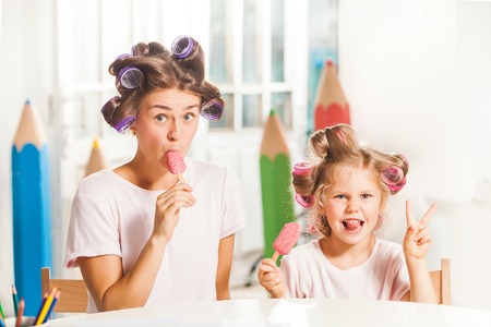 Little girl eating ice cream with her mother on whiteの写真素材