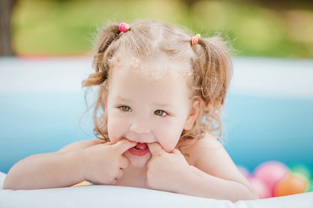 The Two-year old little baby girl playing with toys in inflatable pool in the summer sunny dayの写真素材