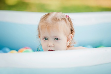 The Two-year old little baby girl playing with toys in inflatable pool in the summer sunny dayの写真素材