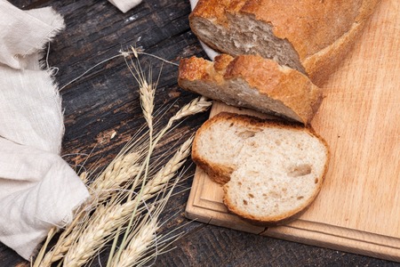 The macro view of rustic bread on an old vintage wooden table. Dark wooden backgroundの写真素材