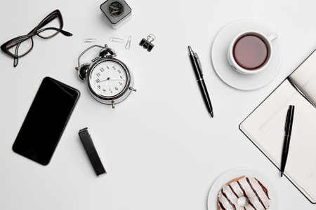 Office desk table with thr cup, supplies, phone on white backgroundの写真素材