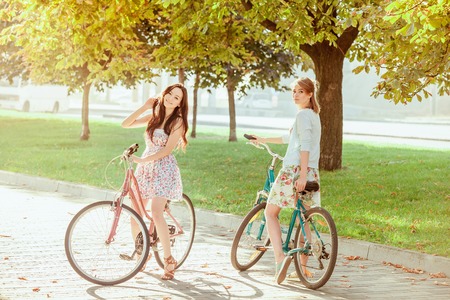 The two young girls with bicycles in park in summerの写真素材