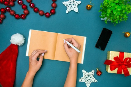 The top view of female hands with pen and Christmas decorationsの写真素材