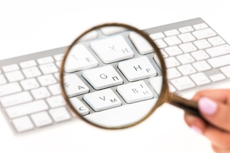 The keyboard of laptop with a magnifying glassの写真素材