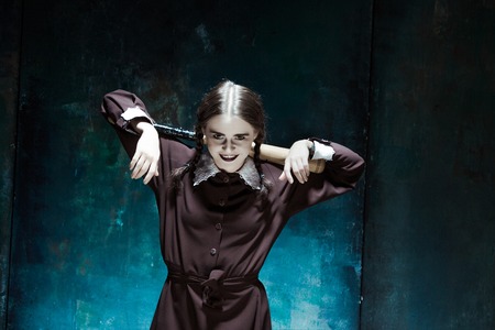 Portrait of a young girl with baseball-bat in school uniform as killer woman against school board . The image in the style of Halloweenの写真素材