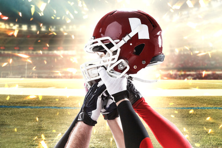 The hands of five american football players with helmet on stadium background