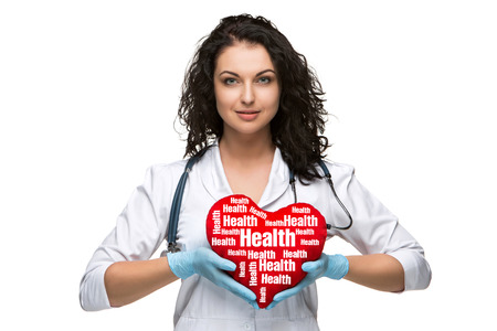 Pretty woman doctor holding a red heart, isolated on white backgroundの写真素材