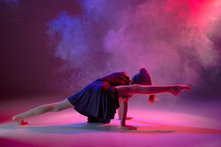 The female teen modern ballet dancer on blue and pink studio background