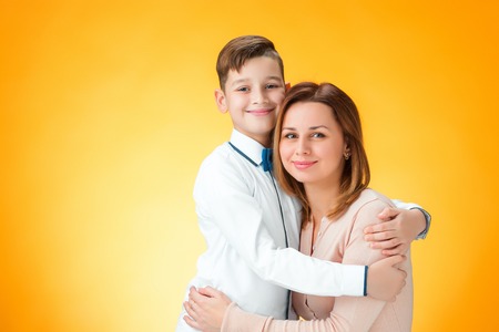 Happy mother and son on orange backgroundの写真素材