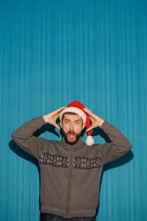 The screaming christmas man wearing a santa hat on the blue studio backgroundの写真素材