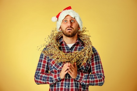 Smiling christmas man wearing a santa hat praying on the orange studio backgroundの写真素材