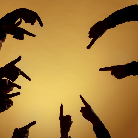 Many silhouettes of hands pointing ahead or out or inside on orange backgroundの写真素材