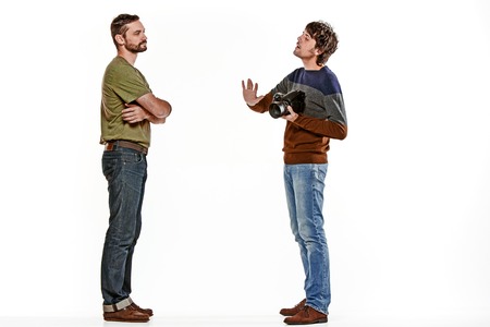 The two male friends with camera on white studio backgroundの写真素材