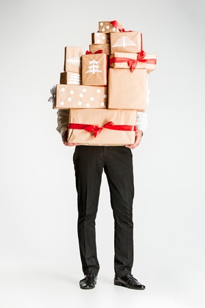 The lot of gift boxes in the hands of young man on white studio backgroundの写真素材
