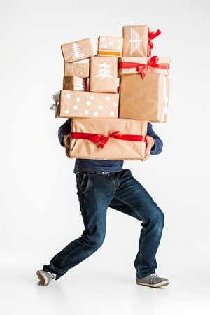 The lot of gift boxes in the hands of young man on white studio backgroundの写真素材